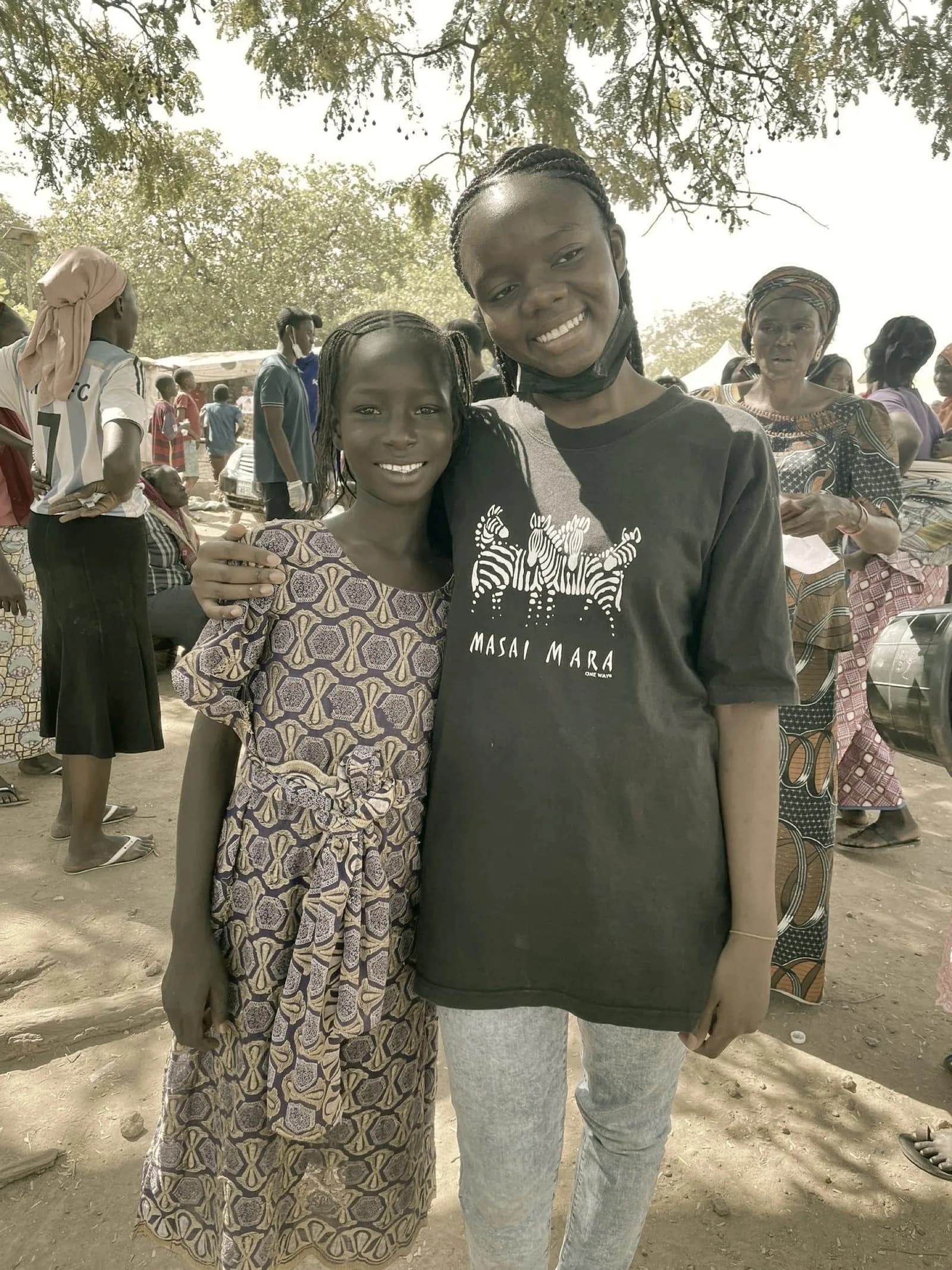 A volunteer and a young community member smiling together at the camp
