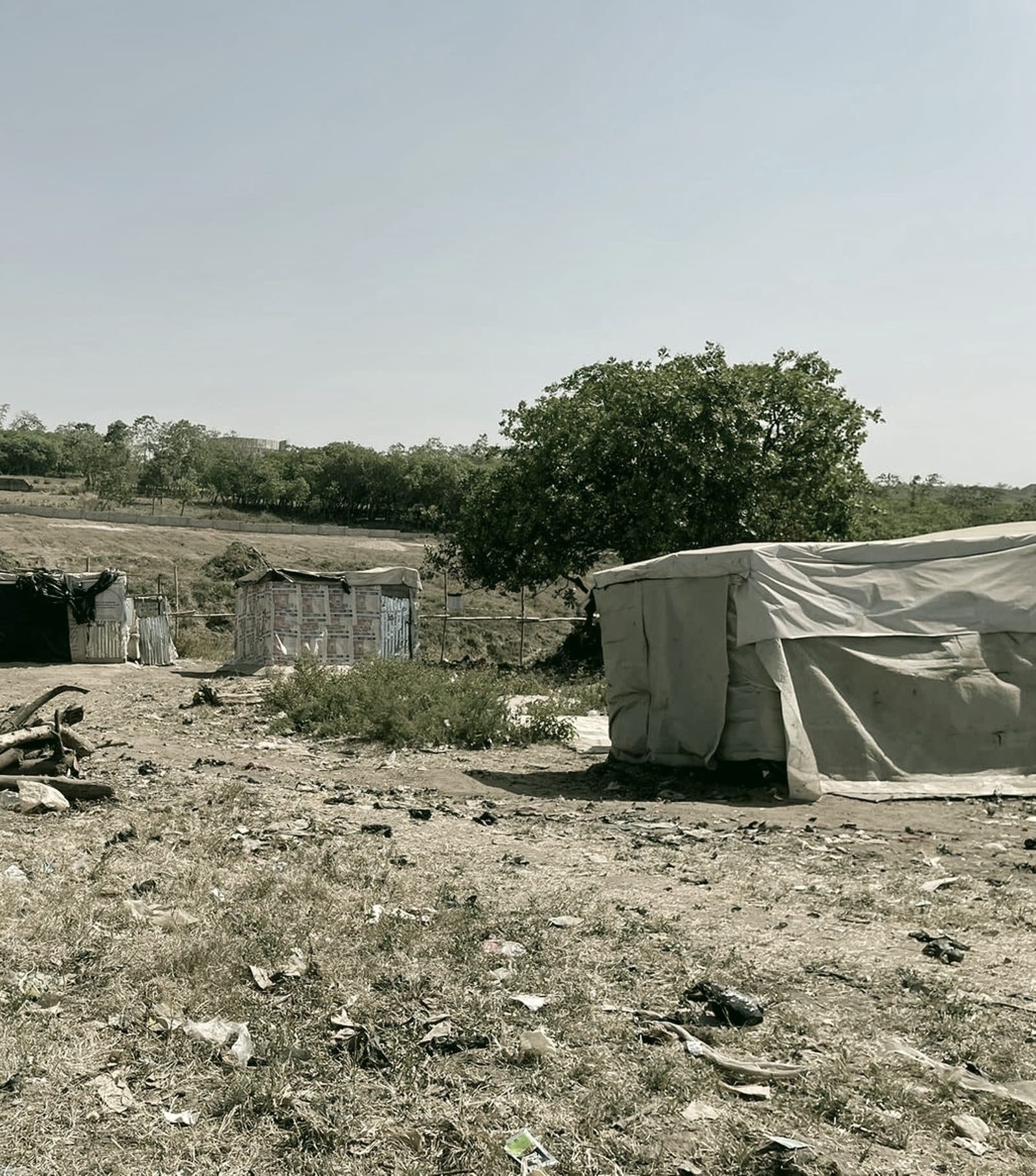 Makeshift shelters and trees on open ground at an informal IDP settlement in Abuja