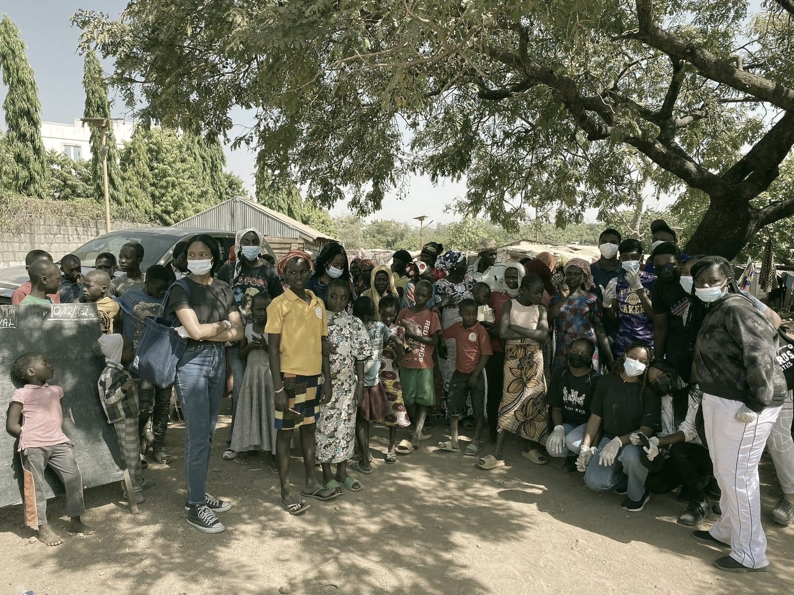 Children, families, and volunteers gathered at the camp beside a chalkboard
