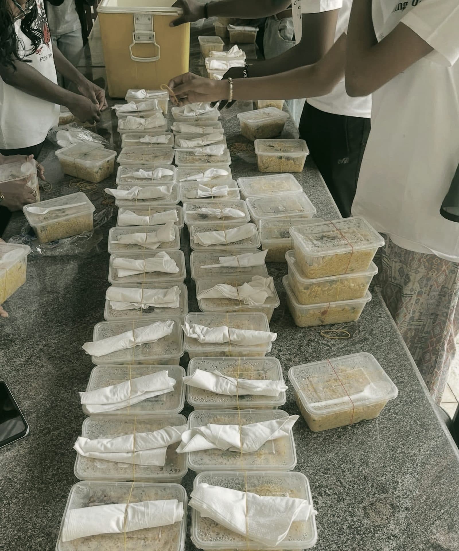 Rows of packed meal containers tied with napkins and spoons, prepared by volunteers