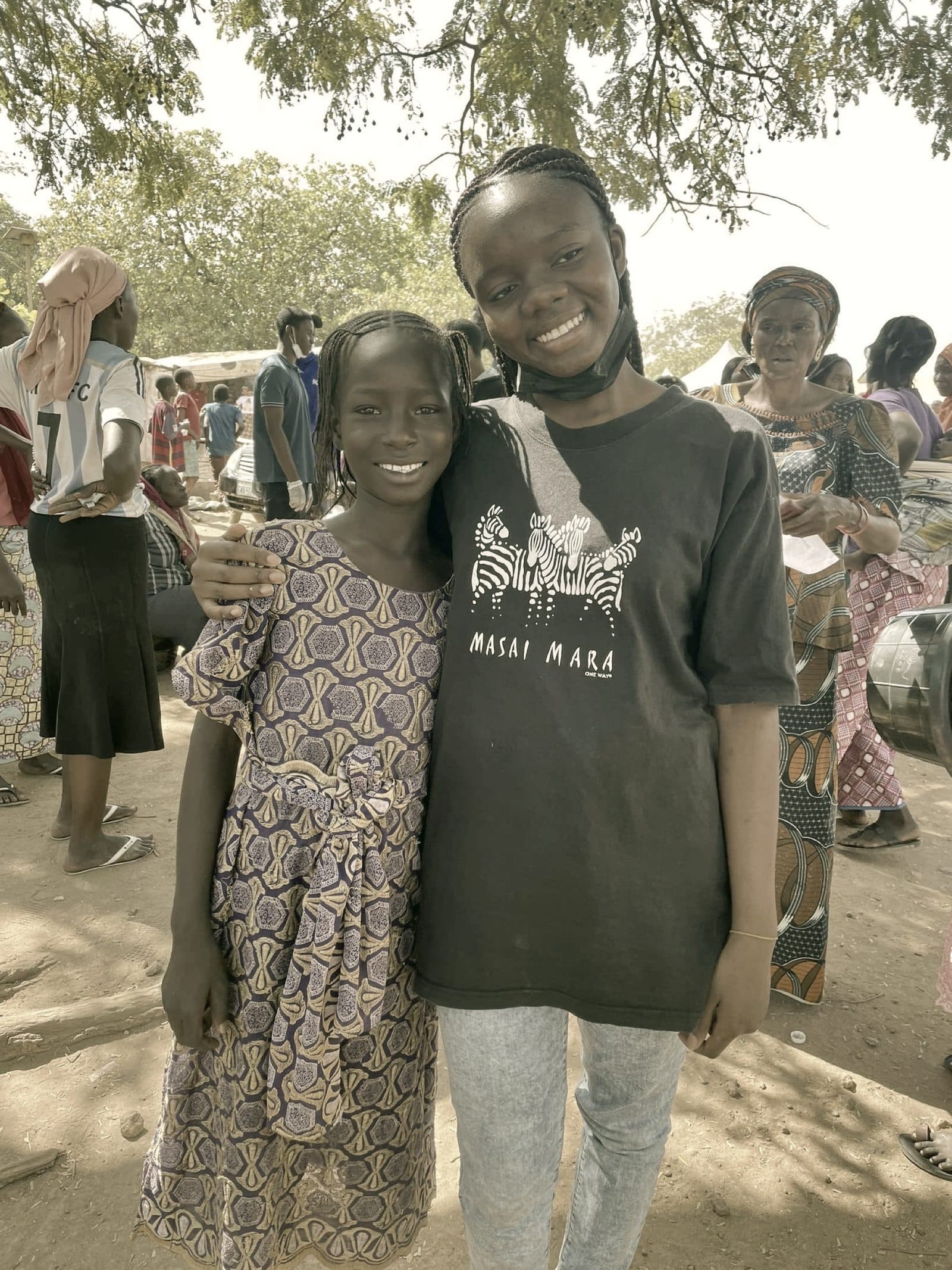 A volunteer and a young community member smiling together at the camp